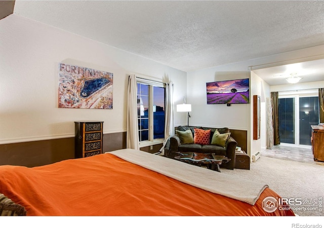 carpeted bedroom featuring a baseboard radiator and a textured ceiling