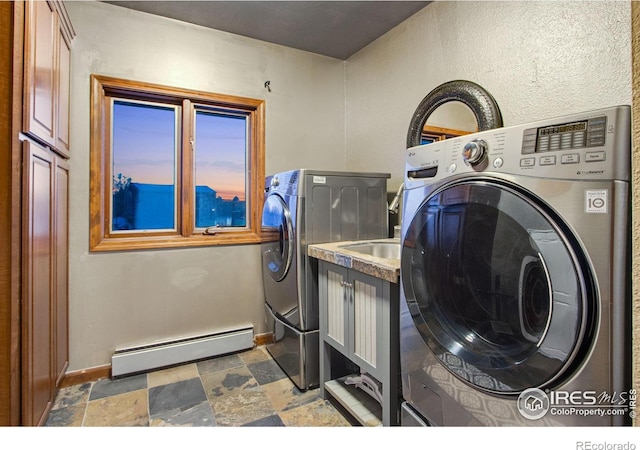 laundry area with baseboard heating, washing machine and dryer, stone finish floor, and baseboards