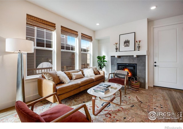 living area featuring recessed lighting, baseboards, a tiled fireplace, and wood finished floors