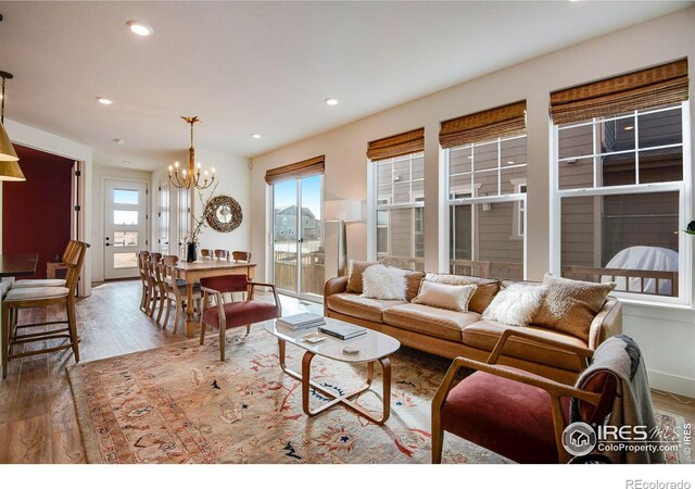 living room with baseboards, recessed lighting, wood finished floors, and an inviting chandelier