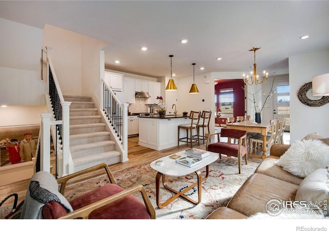 living area featuring light wood-style floors, stairs, a notable chandelier, and recessed lighting