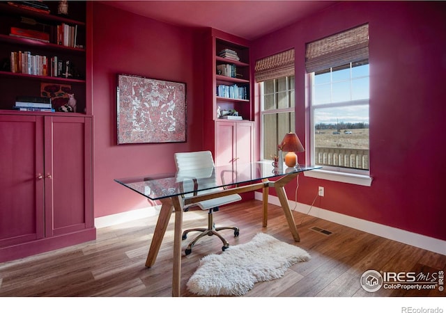 office area featuring visible vents, baseboards, and wood finished floors