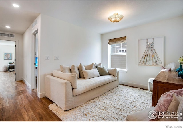 living room featuring baseboards, visible vents, wood finished floors, and recessed lighting