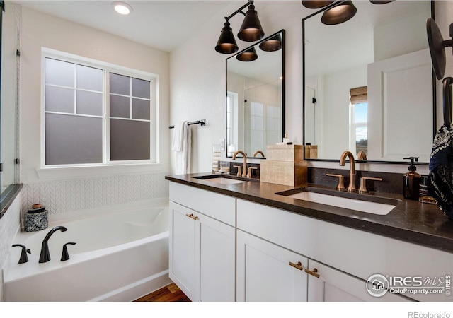 full bath with double vanity, a garden tub, and a sink