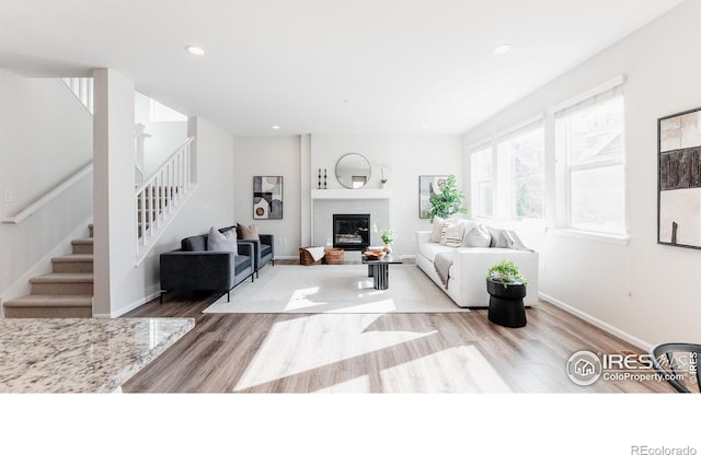 living room featuring recessed lighting, stairway, a glass covered fireplace, wood finished floors, and baseboards