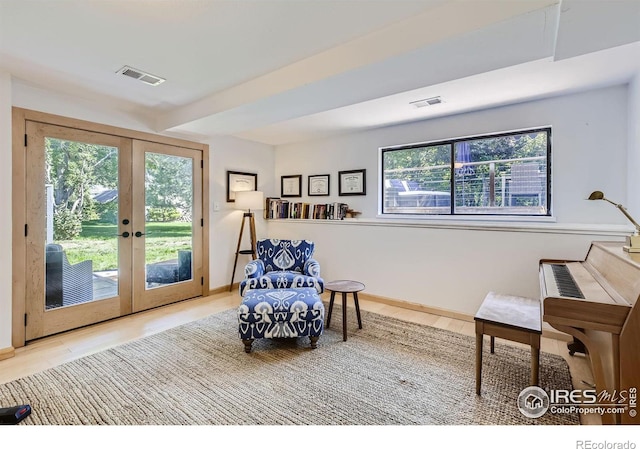 living area featuring baseboards, visible vents, wood finished floors, and french doors