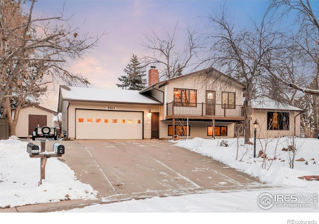 split level home featuring a garage, concrete driveway, a chimney, a storage unit, and an outdoor structure