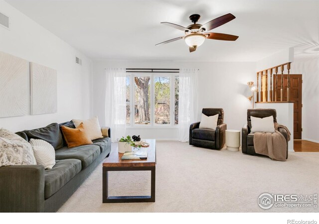 living room featuring carpet, visible vents, and ceiling fan