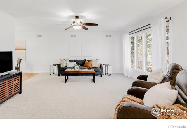 living area featuring carpet, ceiling fan, visible vents, and baseboards