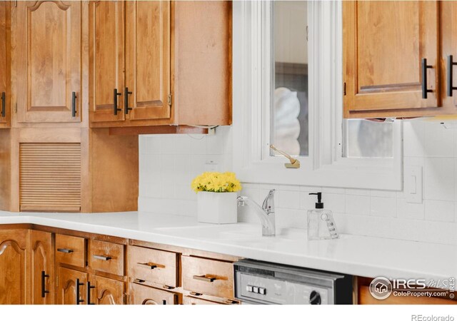 kitchen featuring brown cabinets, light countertops, a sink, and decorative backsplash