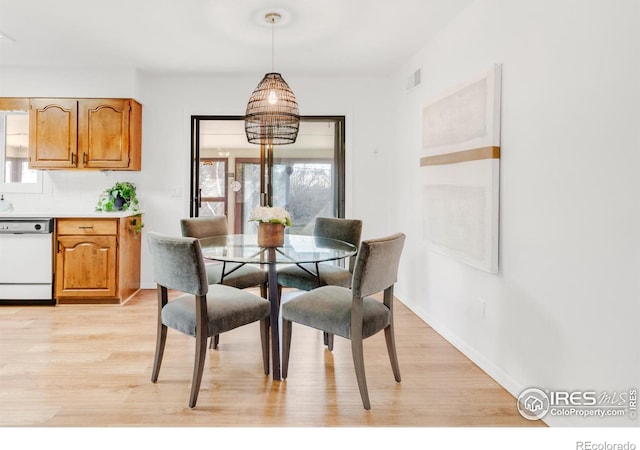 dining room with light wood finished floors, visible vents, and baseboards