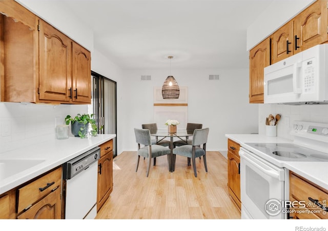 kitchen with light countertops, white appliances, visible vents, and brown cabinets