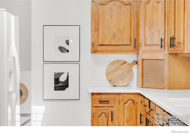 kitchen with white fridge with ice dispenser, light countertops, and decorative backsplash