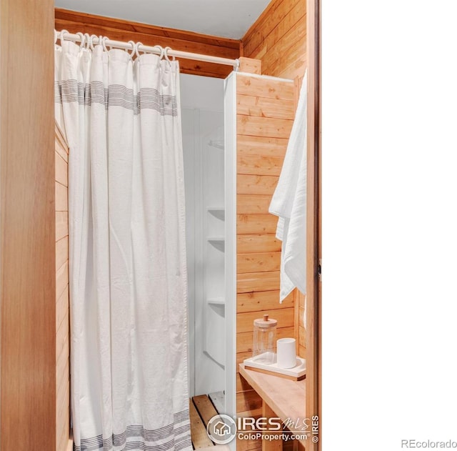 bathroom with wood walls and a shower with curtain