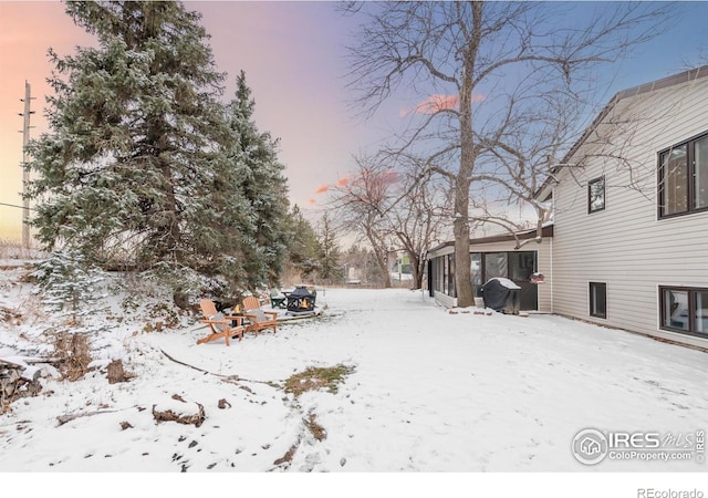 yard layered in snow featuring a sunroom