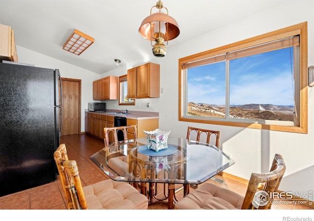 dining room featuring a healthy amount of sunlight, dark tile patterned floors, visible vents, and lofted ceiling