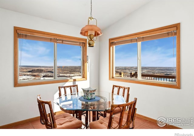 dining room featuring lofted ceiling, baseboards, tile patterned floors, and a healthy amount of sunlight