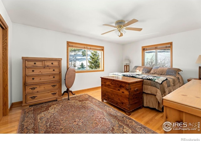 bedroom featuring baseboards, multiple windows, ceiling fan, and light wood finished floors