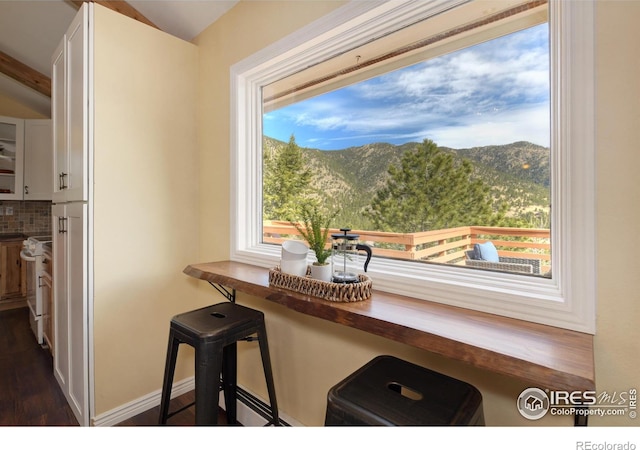 interior details with baseboards, white range oven, a mountain view, and decorative backsplash