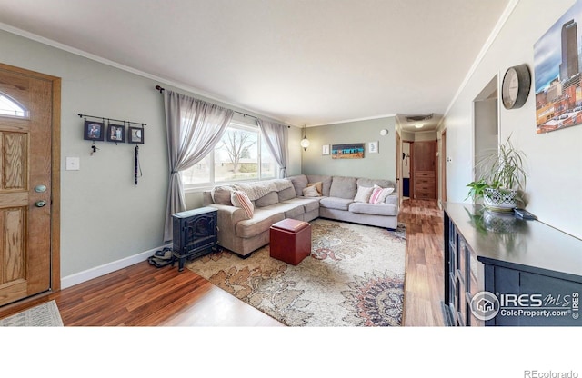 living area with ornamental molding, wood finished floors, visible vents, and baseboards