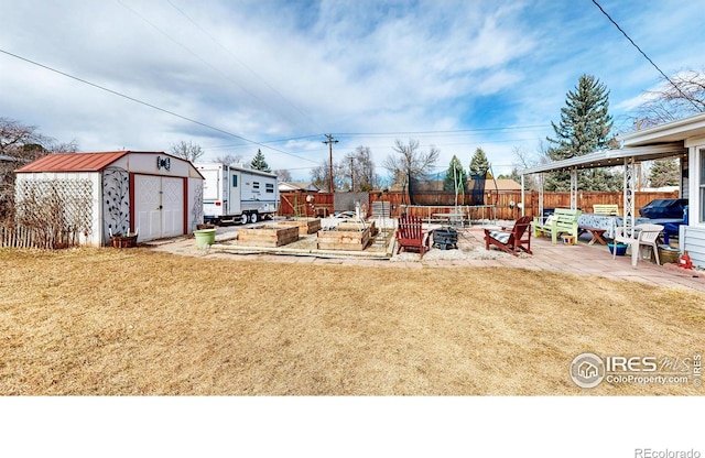 view of yard featuring a vegetable garden, a patio, a fenced backyard, an outdoor structure, and a shed