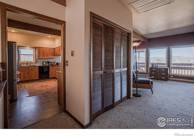 corridor featuring a sink, baseboards, baseboard heating, and dark carpet