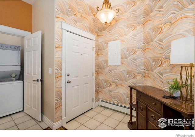 foyer entrance with a baseboard heating unit, wallpapered walls, light tile patterned floors, and stacked washer / drying machine