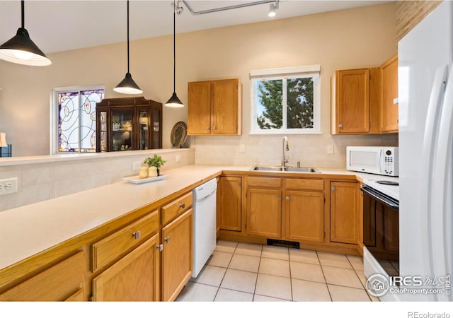 kitchen featuring white appliances, a sink, light countertops, hanging light fixtures, and tasteful backsplash