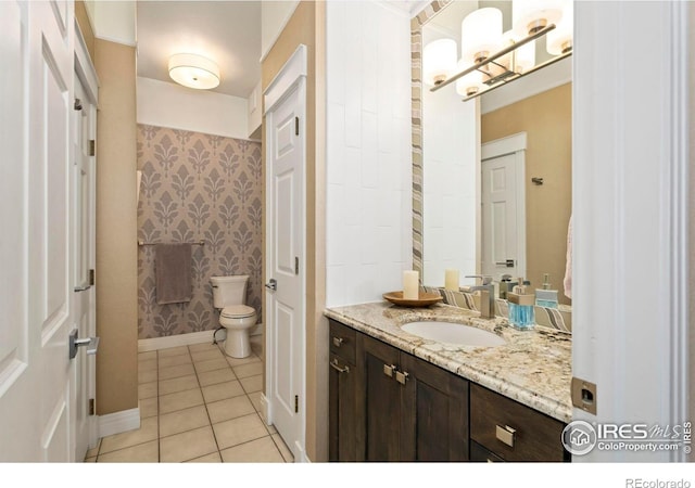 bathroom featuring tile patterned flooring, toilet, vanity, baseboards, and wallpapered walls