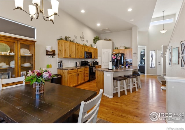 kitchen featuring decorative backsplash, light wood-style floors, a breakfast bar area, a center island, and black appliances