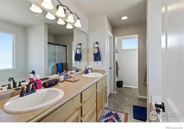 bathroom with double vanity, a shower stall, and a sink