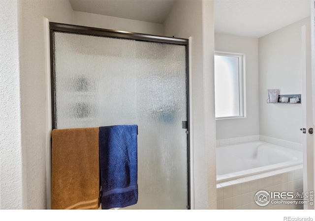 bathroom with a stall shower and a garden tub