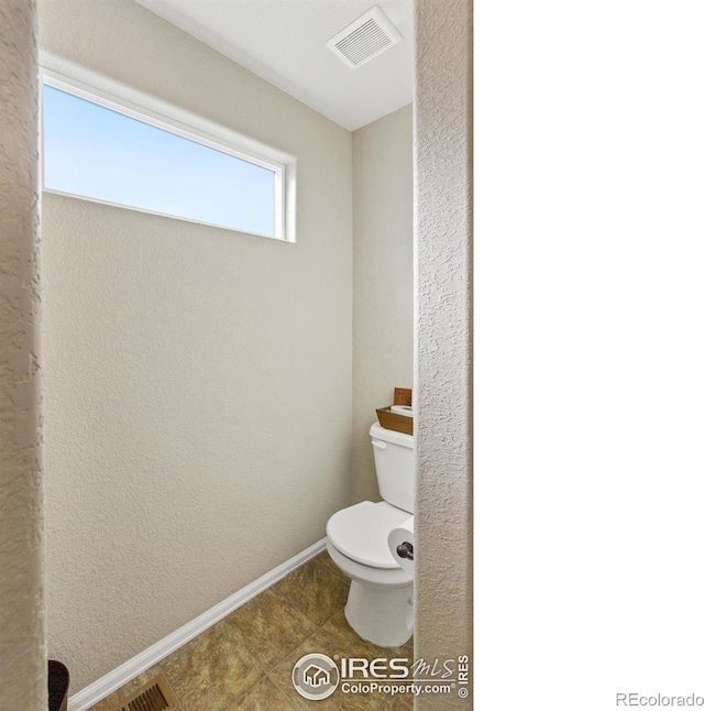 bathroom featuring toilet, tile patterned flooring, visible vents, and baseboards