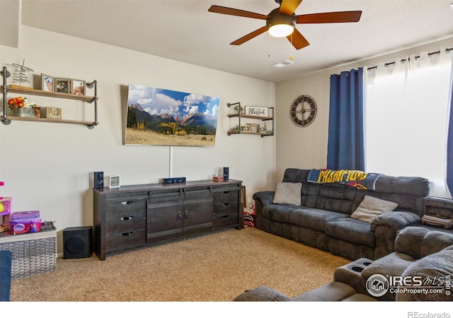 carpeted living area featuring a textured ceiling, visible vents, and a ceiling fan