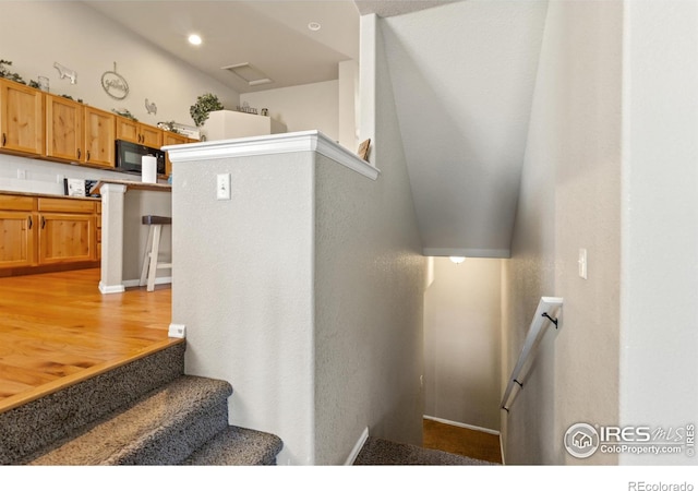 staircase with wood finished floors and recessed lighting