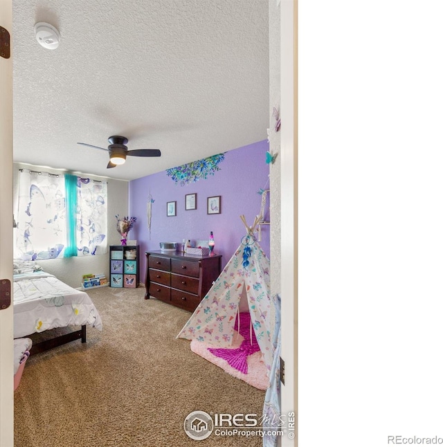 bedroom featuring ceiling fan, a textured ceiling, and carpet flooring