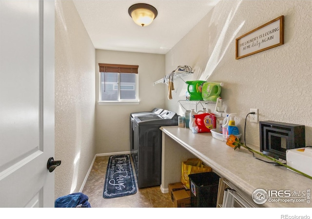 laundry room with baseboards, laundry area, a textured wall, and washer and dryer