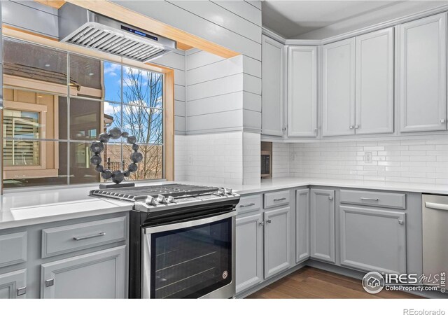 kitchen with light countertops, tasteful backsplash, gray cabinets, and appliances with stainless steel finishes