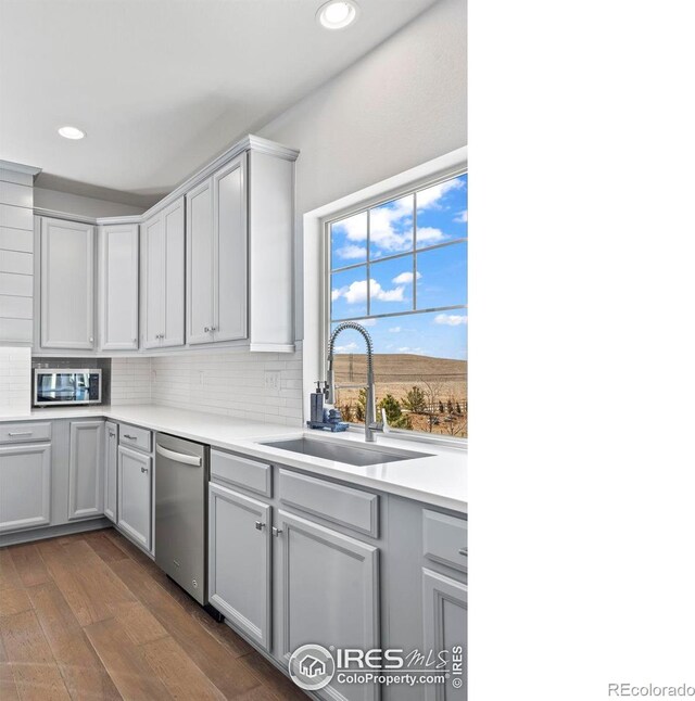 kitchen with dark wood-style floors, stainless steel appliances, backsplash, and a sink