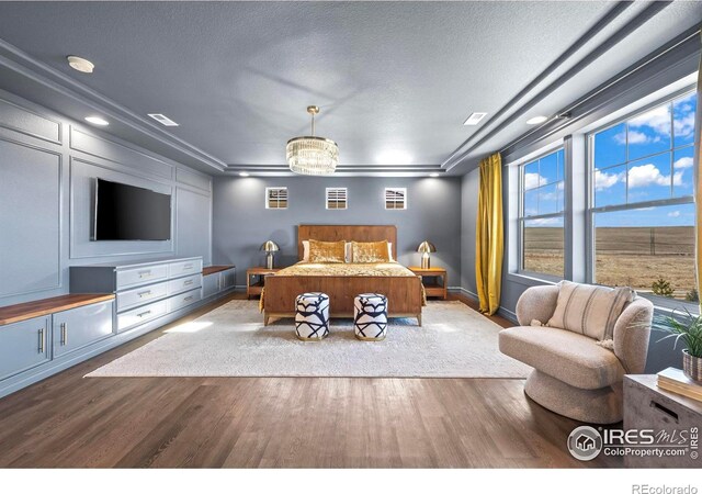 bedroom featuring visible vents, baseboards, a textured ceiling, and wood finished floors