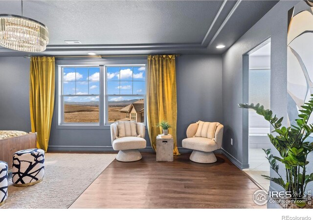 sitting room with visible vents, baseboards, a chandelier, wood finished floors, and a textured ceiling