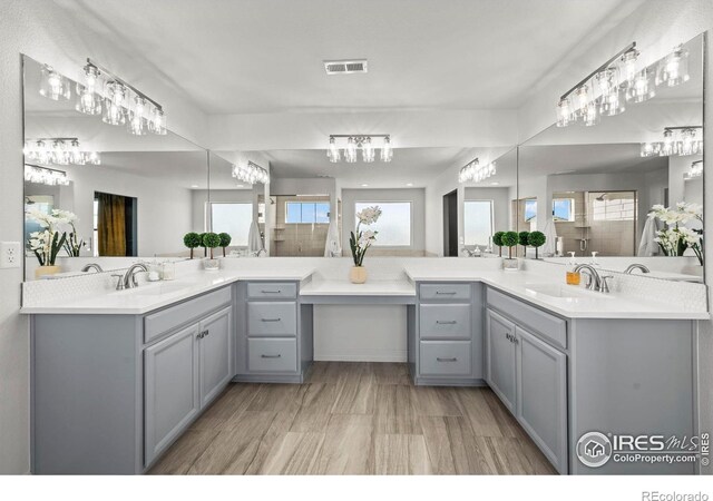 full bathroom featuring a shower stall, two vanities, visible vents, and a sink