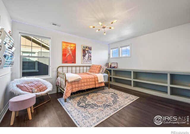 bedroom with a notable chandelier, wood finished floors, and visible vents