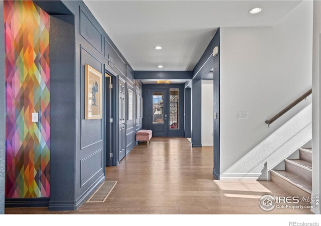 foyer with visible vents, wood finished floors, recessed lighting, baseboards, and stairs