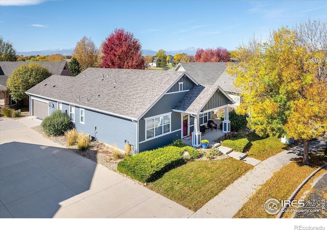 view of front facade with roof with shingles, concrete driveway, board and batten siding, a garage, and a front lawn