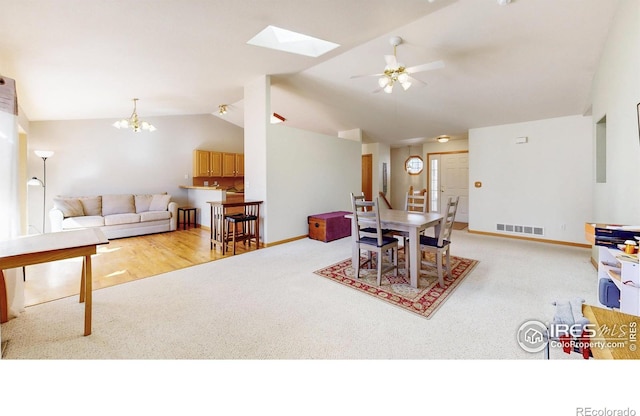 carpeted dining room featuring lofted ceiling, visible vents, baseboards, and ceiling fan with notable chandelier