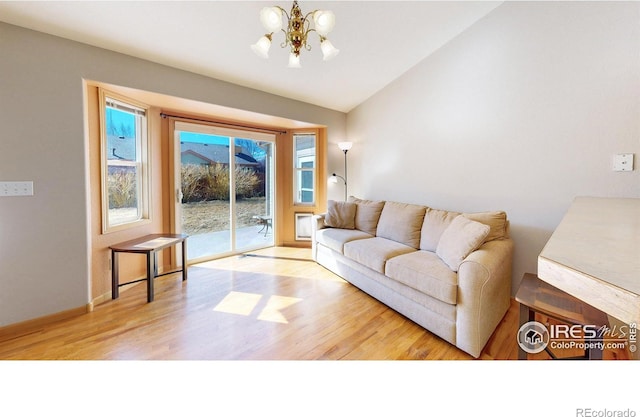 living room with lofted ceiling, wood finished floors, and an inviting chandelier