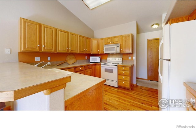 kitchen featuring lofted ceiling, white appliances, light countertops, and a peninsula