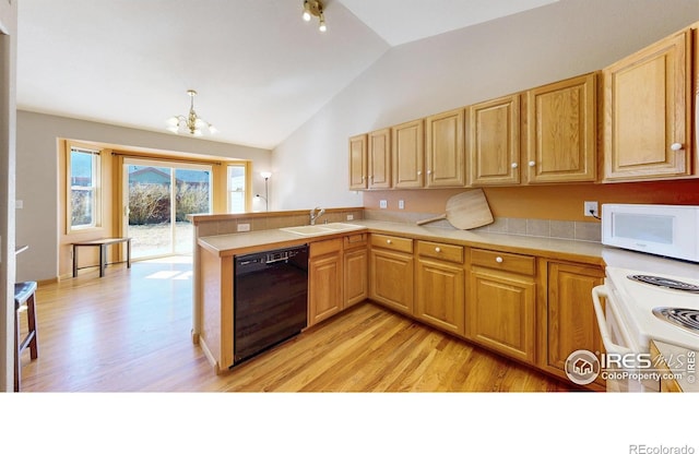 kitchen with a peninsula, white appliances, light wood-type flooring, and a sink