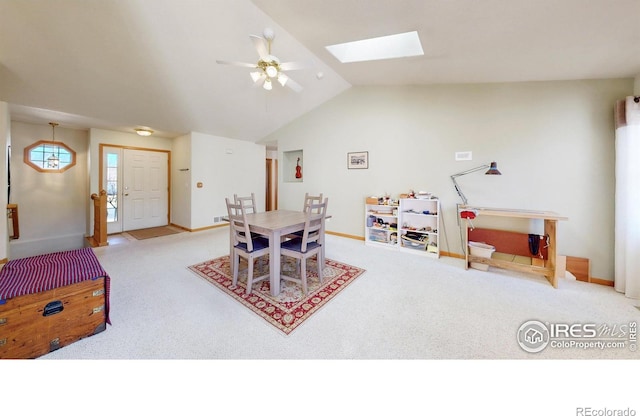 dining space featuring carpet floors, vaulted ceiling with skylight, baseboards, and a ceiling fan